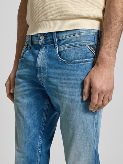 Męski model nosi Slim Fit Jeans im 5-Pocket Design Modell 'Anbass' od Replay z elastycznej bawełny, krój slim fit, zapięcie na guzik i zamek, szerokość w rozmiarze 32/32: 44 cm, długość wewnętrznej nogawki w rozmiarze 32/32: 79 cm, jasnoniebieski denim, tekstura przecierana, zbliżenie na górną część nóg.
