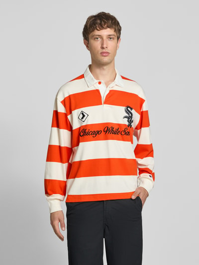 Männermodel trägt Relaxed Fit Poloshirt aus reiner Baumwolle von Champion, breite orange-weiße Blockstreifen, Statement-Stitching, Polokragen, langärmeliges Design, Ganzkörperansicht von vorne.