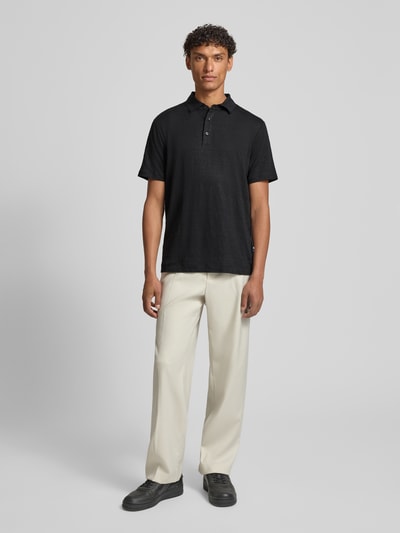 Männermodel trägt Slim Fit Poloshirt aus Leinen-Elasthan-Mix von OLYMP Level Five in Schwarz, Knopfleiste, Halbarm, Ganzkörperansicht von vorne.