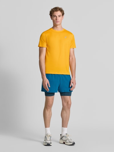 Męski model nosi t-shirt z nadrukiem z logo Model 'CORE' od ASICS TIGER, prosty krój, okrągły dekolt, długość tyłu 72 cm, widok całej sylwetki z przodu