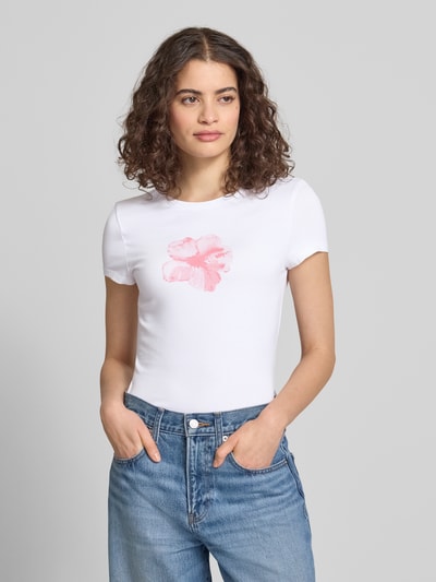 Frauenmodel trägt Schmal geschnittenes T-Shirt aus Baumwollmix mit Blumen-Print von REVIEW, Damen T-Shirt mit Rundhalsausschnitt, kurzärmelig, Rückenlänge 54 cm bei Größe S, Weiß mit rosa Blumen-Print, Ganzkörperansicht von vorne.