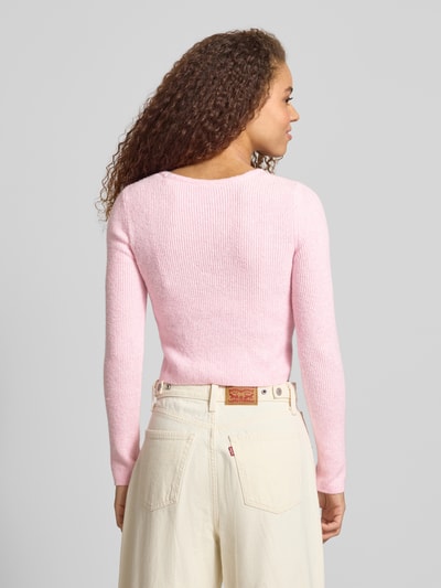 Frauenmodel trägt Regular Fit Strickjacke mit Perl-Optik-Knöpfen Modell 'RICA LIFE' von ONLY in zartem Rosa, Optik: Unifarben, Rippstrick, Passform: Regular-Fit, Verschluss: einreihige Knopfleiste, Ausschnitt: V-Ausschnitt, Ärmelform: Langarm, Materialverarbeitung: Rippstrick, Ganzkörperansicht Rückansicht.