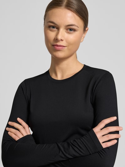 Frauenmodel trägt schwarzes Slim Fit Longsleeve mit Rundhalsausschnitt Modell 'Feather' von Fabletics, elastischer Material-Mix, Nahaufnahme Oberkörper.