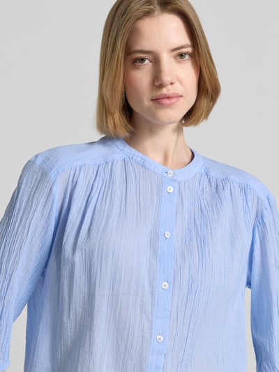 Frauenmodel trägt Relaxed Fit Hemdbluse aus reiner Baumwolle von s.Oliver RED LABEL in hellblauem Hahnentritt-Allover-Muster, Nahaufnahme Oberkörper.
