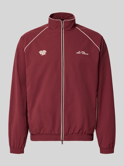 Produktfoto, Trainingsjacke mit Label-Stitching Modell 'Seersucker' von Les Deux in Dunkelrot mit Kontrastpaspeln, gerader Schnitt, Stehkragen, Zwei-Wege-Reißverschluss, elastische Abschlüsse, strukturierte Oberfläche.