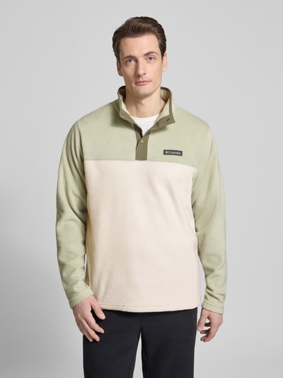 Männermodel trägt Fleecepullover mit Stehkragen und Labeldetail von Columbia in regular fit, Modell STEENS MOUNTAIN, knoopsluiting, kleur lichtgroen/beige; ruglengte maat M 70 cm, mouwlengte 66 cm. Ganzkörperansicht van voren.