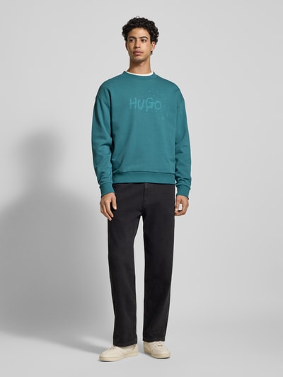 Männermodel trägt Regular Fit Sweatshirt aus reiner Baumwolle Modell 'NIEROFIX_CREW' von Hugo Blue in Unifarben mit Label-Print, Rundhals, langarm, geripptem Rumpfabschluss, Sweat-Material; Ganzkörperansicht von vorne.