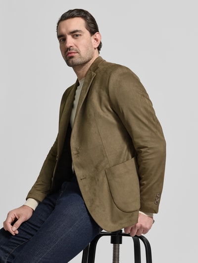Männermodel trägt Regular Fit Sakko mit Reverskragen Modell 'Benito' von CINQUE in Olivbraun, glatte Textur, Nahaufnahme Oberkörper. Elastischer Material-Mix, 2-Knopf, aufgesetzte Taschen, Rückenlänge 73 cm, Schulterbreite 45 cm, Ärmellänge 65 cm.
