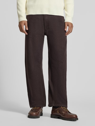 Männermodel trägt dunkelbraune Straight Fit Stoffhose aus Baumwoll-Mix Modell 'GONAGO' von DRYKORN, strukturierte Oberfläche, Nahaufnahme Unterkörper, Herren Stoffhose mit Eingrifftaschen, Knopf- und Reißverschluss, elastisches Material, Kontext: Bundweite 45 cm, Innenbeinlänge 69 cm.