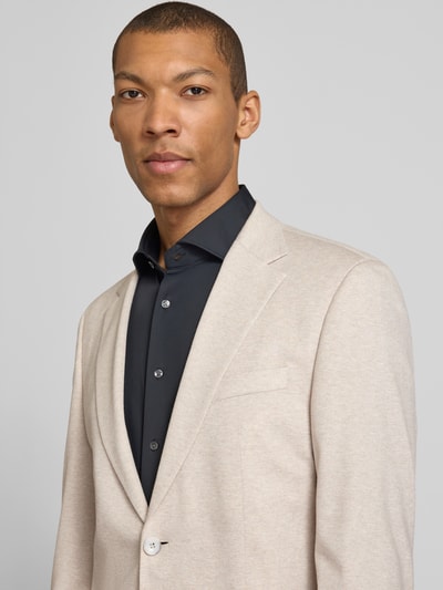 Männermodel trägt Slim Fit Anzugsakko aus Viskose-Mix Modell 'ARNDT4-J 2' von Strellson in Beige-Melange, Nahaufnahme Oberkörper.