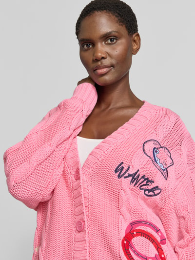 Vrouwenmodel draagt cardigan met Motiefstitchings en v-hals van Milano Italy, katoenmix, loose fit, knoopsluiting, ruglengte maat S 74 cm, mouwlengte 57 cm, detailopname bovenlichaam.
