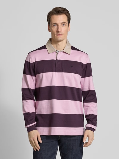 Männermodel trägt Regular Fit Poloshirt mit Streifenmuster und Label-Stitching von Fynch-Hatton in Rosa und Dunkellila, Baumwolle, Ganzkörperansicht von vorne.