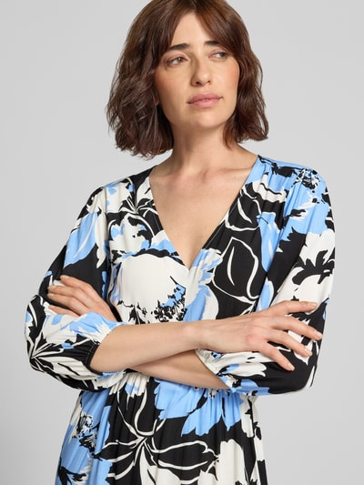 Frauenmodel trägt Knielanges Kleid aus Viskose im Allover-Look Modell 'Fe44li' von ZABAIONE mit V-Ausschnitt, 3/4-Arm, Blumenmuster in Blau, Schwarz und Weiß, Nahaufnahme Oberkörper.