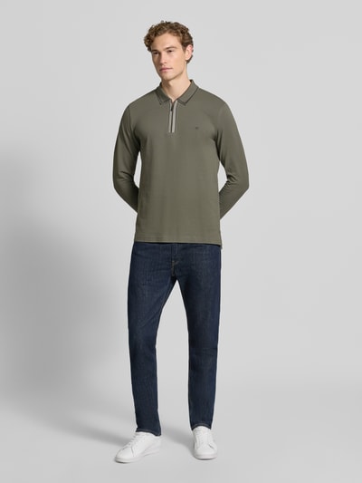 Männermodel trägt Slim Fit Poloshirt mit Reißverschluss von Christian Berg Men in Olivgrün aus Baumwolle, Longsleeve, Ganzkörperansicht von vorne.