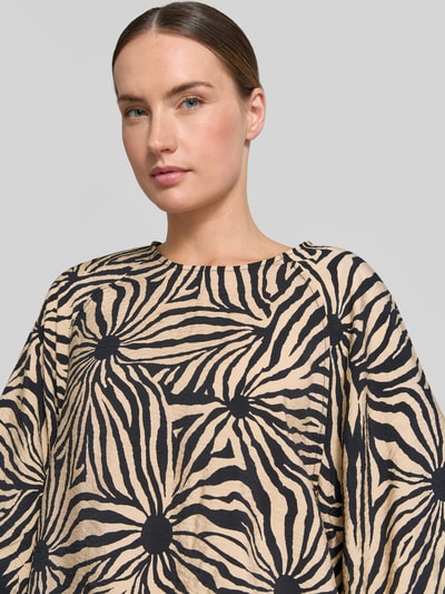 Frauenmodel trägt Regular Fit Bluse aus Viskose-Mix im Allover-Look von Christian Berg Woman, beiges Schwarzmuster, Nahaufnahme Oberkörper.