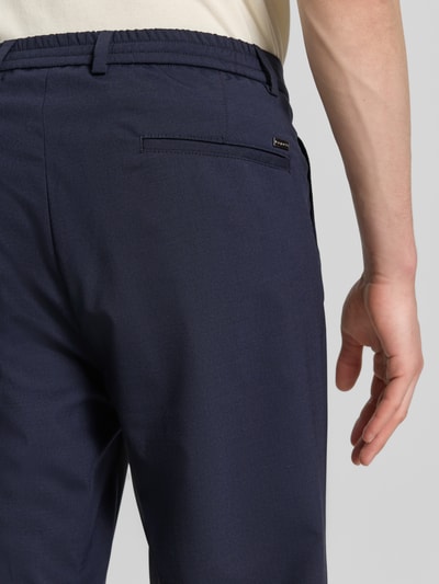 Mężczyzna nosi Loose Fit Hose mit Gesäßtaschen von bugatti, mieszanka bawełny i wełny, elastyczny pas, kolor granatowy, detal kieszeni z tyłu, zbliżenie tylnych partii.