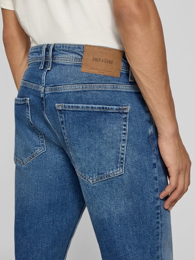 Männermodel trägt Straight Fit Jeans aus Baumwoll-Mix Modell 'SEDGE' von ONLY & SONS in Mittelblau, Detailaufnahme Rückansicht.