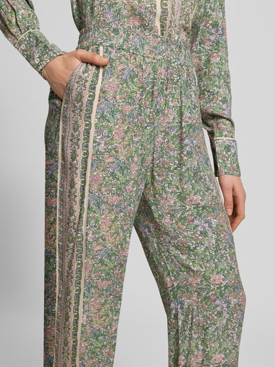Frauenmodel trägt Stoffhose aus Viskose im Allover-Look Modell 'Bala' von MOS MOSH, grün mit floralem Muster, elastischer Bund, Nahaufnahme Oberkörper.