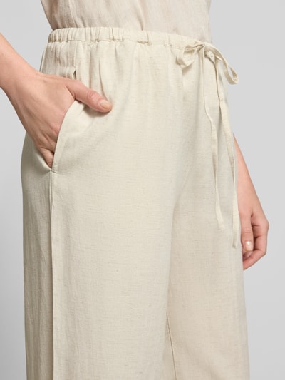 Frauenmodel trägt Stoffhose aus Viskose-Mix Modell 'PRISILLA' von Vila in Beige mit Eingrifftaschen und Tunnelzug, Nahaufnahme Oberkörper.