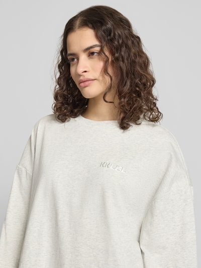 Frauenmodel trägt Oversized Longsleeve in Layering-Optik von Karo Kauer aus reiner Baumwolle, meliertes Hellgrau, Label-Stitching, Rundhalsausschnitt, Nahaufnahme Oberkörper.