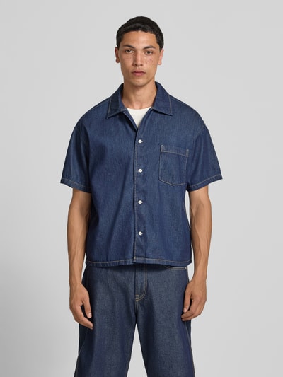 Männermodel trägt Modern Fit Jeanshemd mit Brusttasche Modell 'AUSTIN' von Jack & Jones aus reiner gewachster Baumwolle, Ganzkörperansicht von vorne.