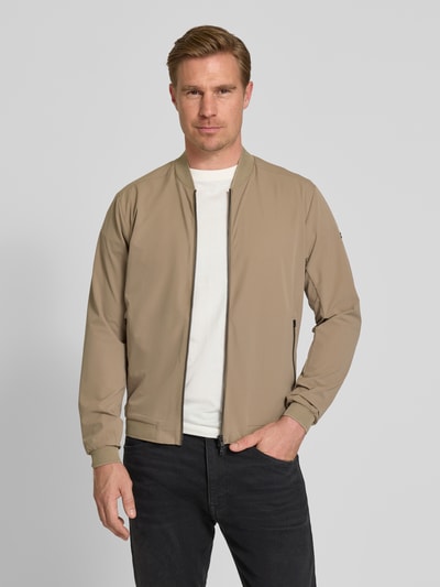 Männermodel trägt beige Regular Fit Jacke mit Stehkragen Modell 'Campo' von SCANDINAVIAN EDITION, Zweiwege-Reißverschluss, Eingrifftaschen, elastische Abschlüsse, Rückenlänge 67 cm, Schulterbreite 44 cm, Brustweite 51 cm, Ärmellänge 64 cm, Ganzkörperansicht von vorne.