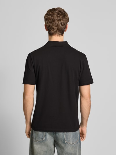 Männermodel trägt Regular Fit Poloshirt mit Logo-Stitching von adidas Originals in Schwarz, reine Baumwolle, Rückenansicht, Ganzkörperansicht Rückansicht.