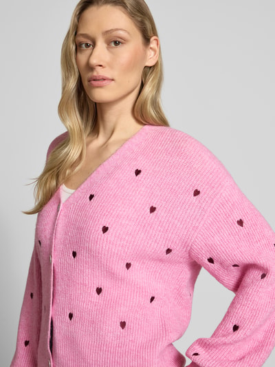 Vrouwenmodel draagt Regular Fit Cardigan met Escorial Woll-Anteil model 'Fleur' van YAS, roze met all-over motiefstitching, V-hals, knoopsluiting, elastische materiaalmix met wol, tricotlook, Nahaufnahme bovenlichaam.