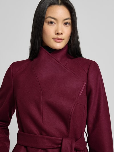 Frauenmodel trägt Mantel mit Stehkragen Modell 'ROSE' von Ted Baker aus Woll-Mix mit Kaschmir-Anteil, Regular-Fit, Knopfverschluss, Taillengürtel, Eingrifftaschen, Farbe Bordeaux, Nahaufnahme Oberkörper.