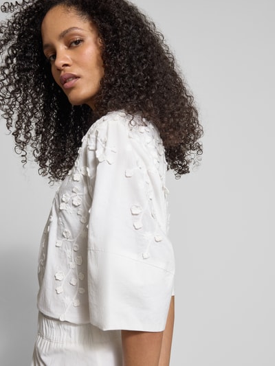 Frauenmodel trägt Bluse mit floraler Zier-Applikation von JAKE*S STUDIO WOMAN in Weiß, lockere Passform, Nahaufnahme Oberkörper.