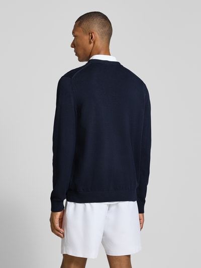 Männermodel trägt Regular Fit Pullover aus Baumwoll-Mix von Lacoste in Dunkelblau, weiße Shorts, Ganzkörperansicht Rückansicht.