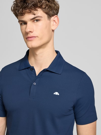 Männermodel trägt Slim Fit Poloshirt mit Logo Modell 'EDMOND' von Ellesse, Material-Mix mit Stretch-Anteil, Nahaufnahme Oberkörper.