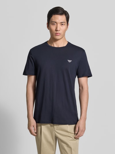 Männermodel trägt T-Shirt mit Logo-Patch und Rundhalsausschnitt von Emporio Armani in Dunkelblau, Modern Fit, glatte Baumwolle, Ganzkörperansicht von vorne.