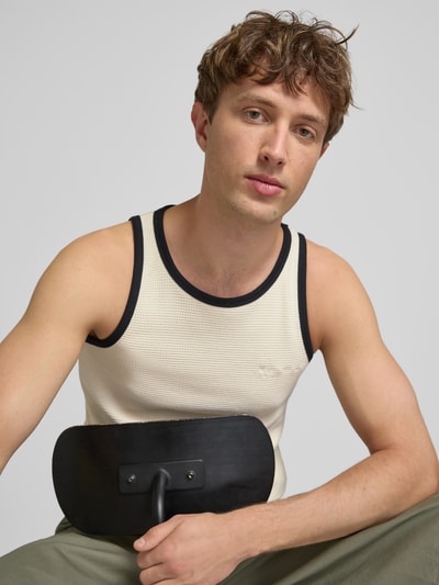 Männermodel trägt Slim Fit Top mit Rundhalsausschnitt von KARL KANI aus Reine Baumwolle, Logo-Stitching, Strukturmuster, Nahaufnahme Oberkörper.