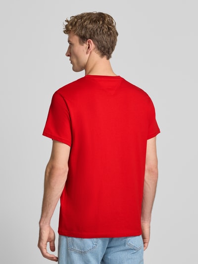 Männermodel trägt Slim Fit T-Shirt aus reiner Baumwolle von Tommy Jeans in kräftigem Rot, glatte Struktur, Ganzkörperansicht Rückansicht.