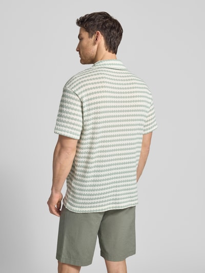 Männermodel trägt Relaxed Fit Poloshirt aus Baumwoll-Mix Modell 'DYLAN' von SELECTED HOMME, Optik:Allover-Muster, Ganzkörperansicht Rückansicht.