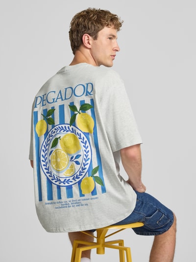 Männermodel trägt Oversized T-Shirt mit Backprint und Rundhalsausschnitt von PEGADOR aus reiner Baumwolle, Label-Print, Rückansicht.