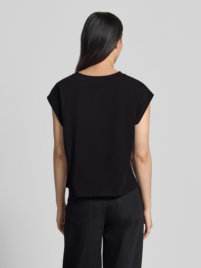 Frauenmodel trägt Blusenshirt mit Knotendetail von Christian Berg Woman Selection aus schwarzem Satin, Regular-Fit, Rundhalsausschnitt, Rückenlänge 52 cm bei Größe 36, Ganzkörperansicht Rückansicht.
