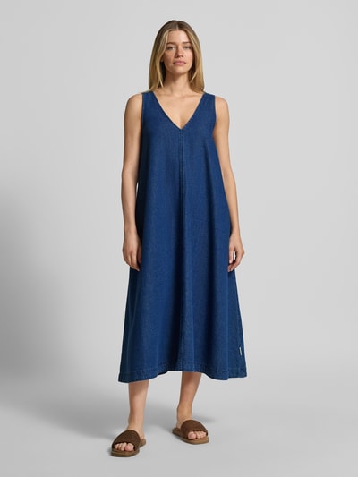Vrouwenmodel draagt Loose fit Jeanskleid aus Baumwoll-Lyocell-Mix van Armedangels in denimlook, mix van katoen en lyocell, midilengte, brede bandjes, V-hals, steekzakken, twill materiaalverwerking, labelpatch. Ganzkörperansicht van voren.