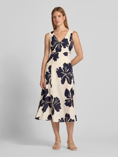 Frauenmodel trägt Midikleid aus Viskose-Mix Modell 'Olimpio' von MANGO mit taillierter Passform, Cut-Outs, floraler Allover-Print in Dunkelblau auf cremefarbenem Grund, ärmellos, V-Ausschnitt, Ganzkörperansicht von vorne.