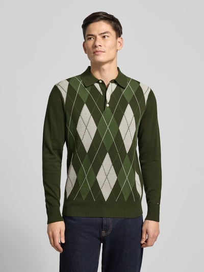 Männermodel trägt Regular Fit Strickpullover aus reiner Baumwolle von Tommy Hilfiger, Optik: Unifarben, Gitterkaro, Langarm, Polokragen, Passform: Regular-Fit, Struktur: Strick, Material: reine Baumwolle; Label-Stitching-Applikation, Farben: Grün und Weiß, Ärmel- und Rumpfabschluss gerippt, Ganzkörperansicht von vorne.