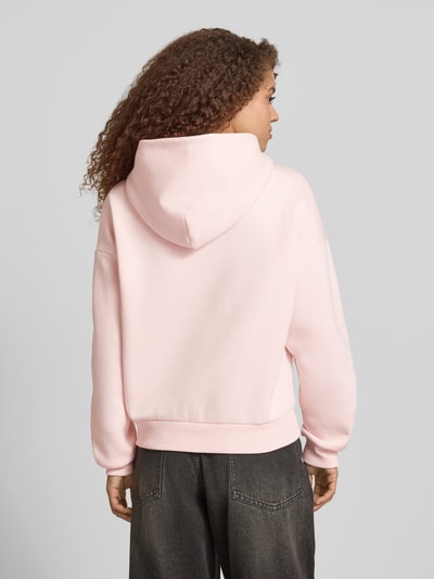 Vrouwenmodel draagt Hoodie met Logo-Print en Känguru-Tasche van REVIEW in lichtroze katoenmix, loose fit, capuchon, rugaanzicht