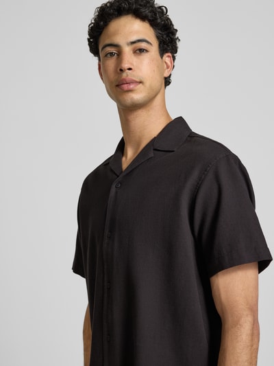 Männermodel trägt Regular Fit Freizeithemd mit Strukturmuster Modell 'Global' von Jack & Jones aus reiner Baumwolle, Kurzärmelig, Reverskragen, Knopfleiste, Nahaufnahme Oberkörper.