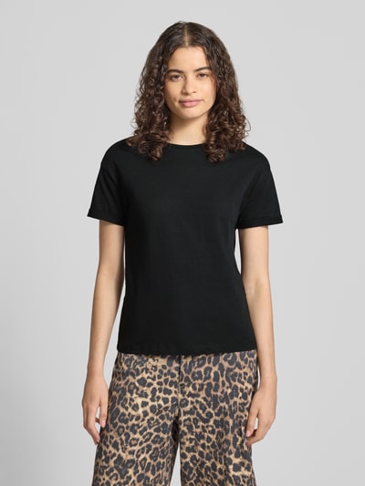 Kobiece modelka nosi damski t-shirt o prostym kroju z okrągłym dekoltem, zakładka na rękawach, model 'BRANDY' od NOISY MAY®, czarny kolor, długość tyłu w rozmiarze S: 59 cm, pełen widok od przodu.