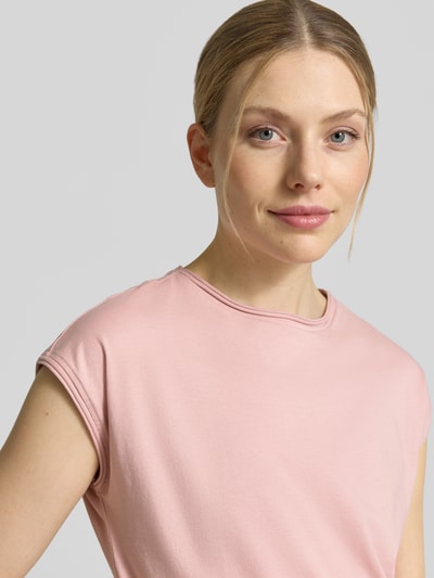 Frauenmodel trägt T-Shirt mit Rundhalsausschnitt und Rollsaum von Christian Berg Woman in Rosa aus reiner Baumwolle, Nahaufnahme Oberkörper.