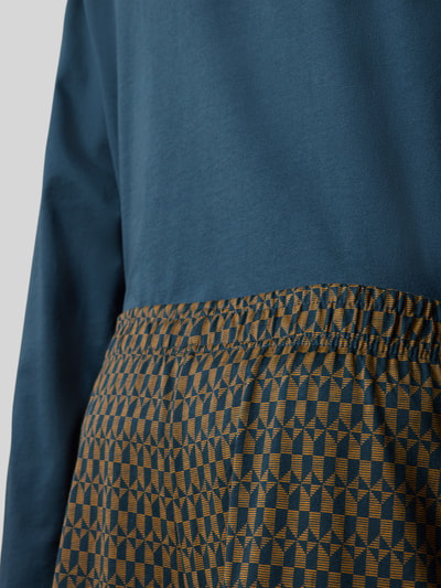 Männermodel trägt Regular Fit Pyjama-Set aus reiner Baumwolle von SCHIESSER in Blau und Braun, Nahaufnahme Oberkörper, Herren Pyjama-Set.