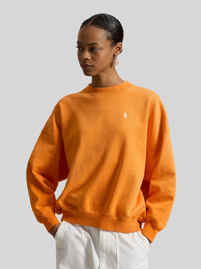Frauenmodel trägt Oversized Sweatshirt aus Baumwoll-Mix von Polo Ralph Lauren in Orange mit Logo-Stitching, Ganzkörperansicht von vorne.