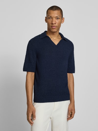 Männermodel trägt Regular Fit Poloshirt aus Bio-Baumwoll-Mix Modell 'BOUCLE' von Armedangels, dunkelblau, Bouclé-Strick, unifarben, Label Patch, Ganzkörperansicht von vorne.