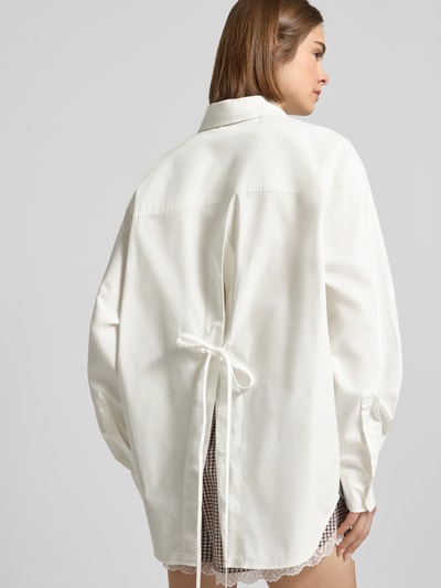 Frauenmodel trägt Oversized Hemdbluse mit Statement-Stitching Modell 'Leya' von OH APRIL aus Reine Baumwolle, Oversized-Fit, Rückenansicht.