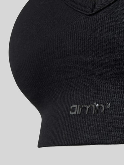 Frauenmodel trägt Bustier mit Stretch-Anteil von aim'n in Schwarz, breiter Ripp-Bund, Label-Detail, Nahaufnahme Oberkörper.